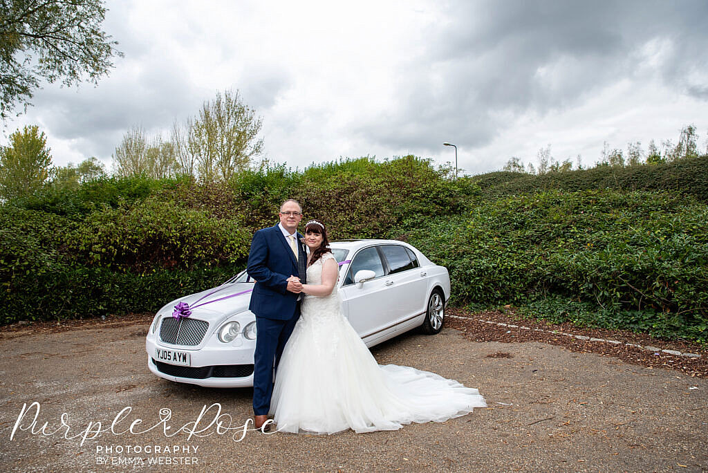 Bride and groom in front of their car