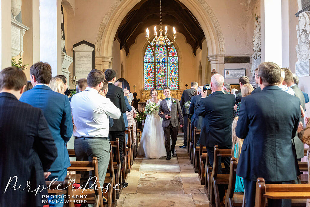 Bride and groom arm in arm leaving the church