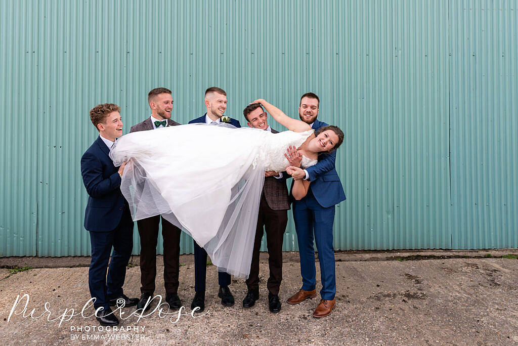 Groomsmen carrying the bride