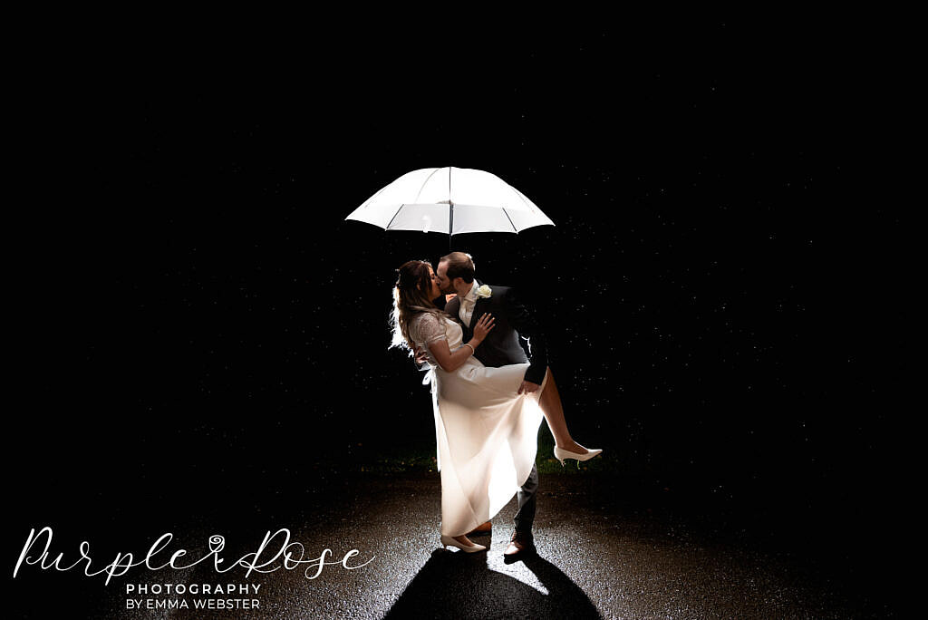 Bride and groom kissing in the rain