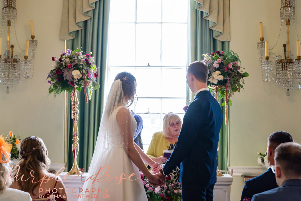 Photo of bride and groom holding hands during their wedding ceremony