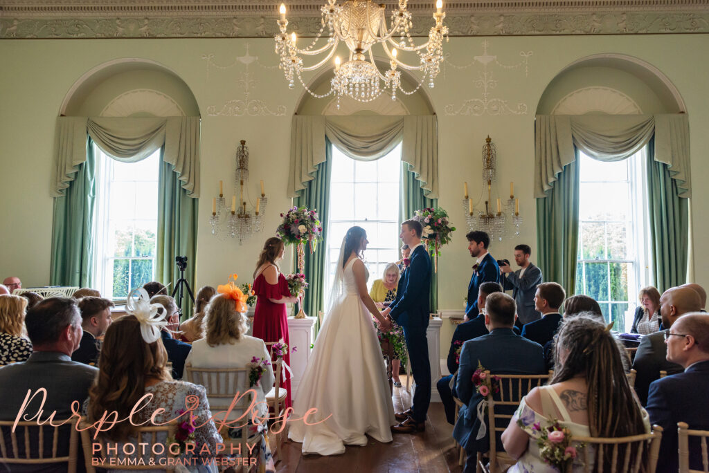 Photo of bride and groom stood in front of a tall window on their wedding day in Milton Keynes