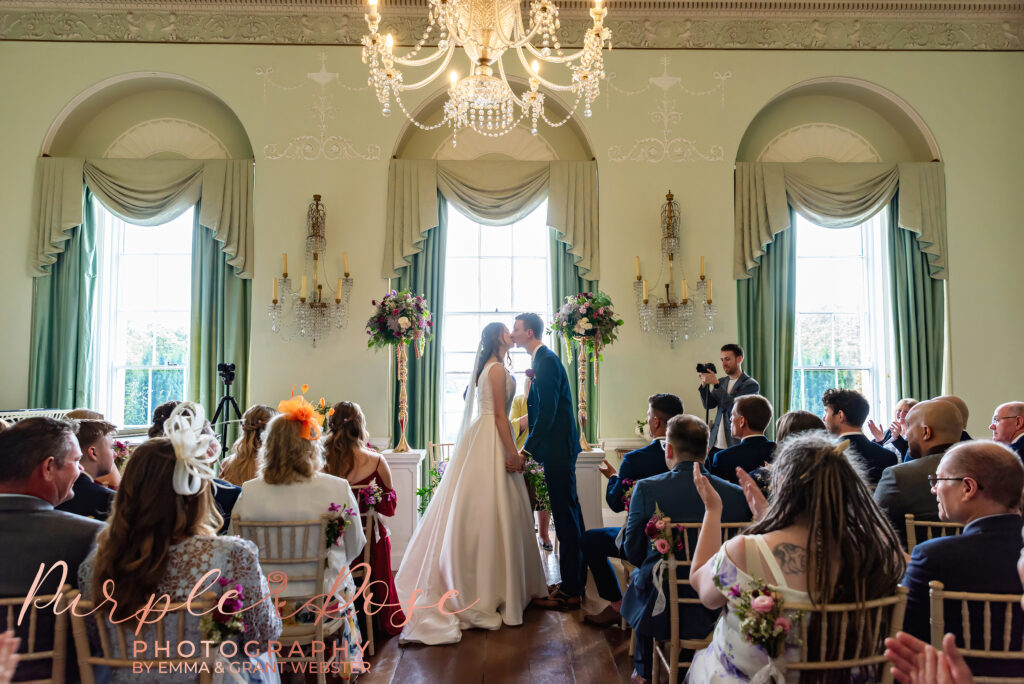 Photo o fbride and groom sharing their first kiss on their wedding day in Milton Keynes