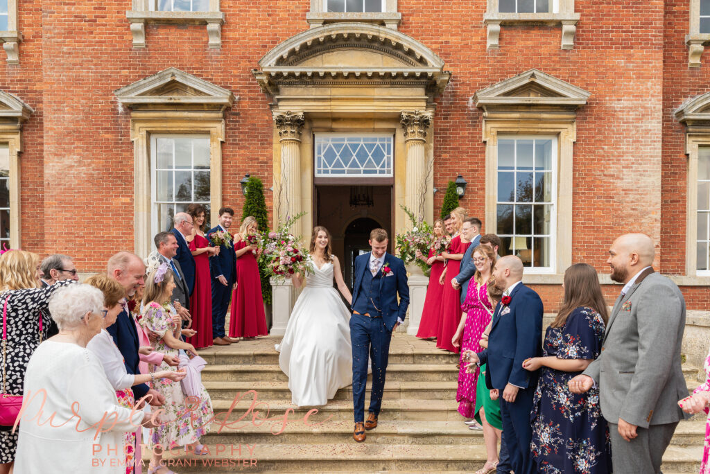 Photo of bride and groom walking down the steps of their wedding venue in Milton Keynes