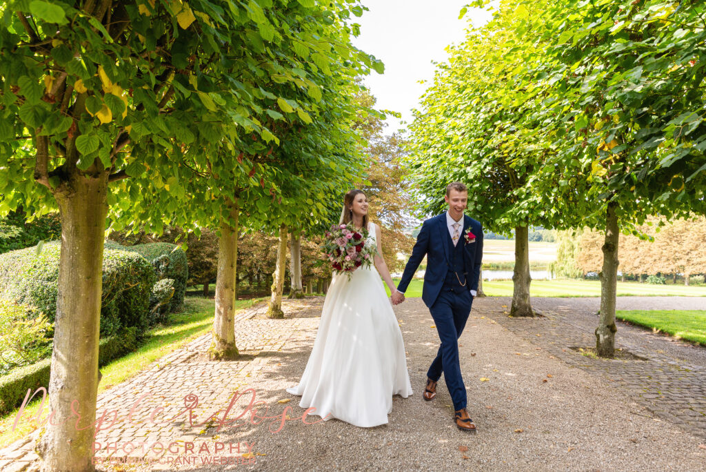 Photo of bride and groom walking in the gardens of their wedding venue in Milton Keynes