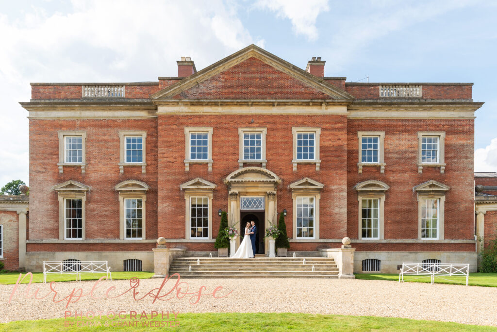 Photo of bride and groom stood on the steps of their wedding venue in Milton Keynes