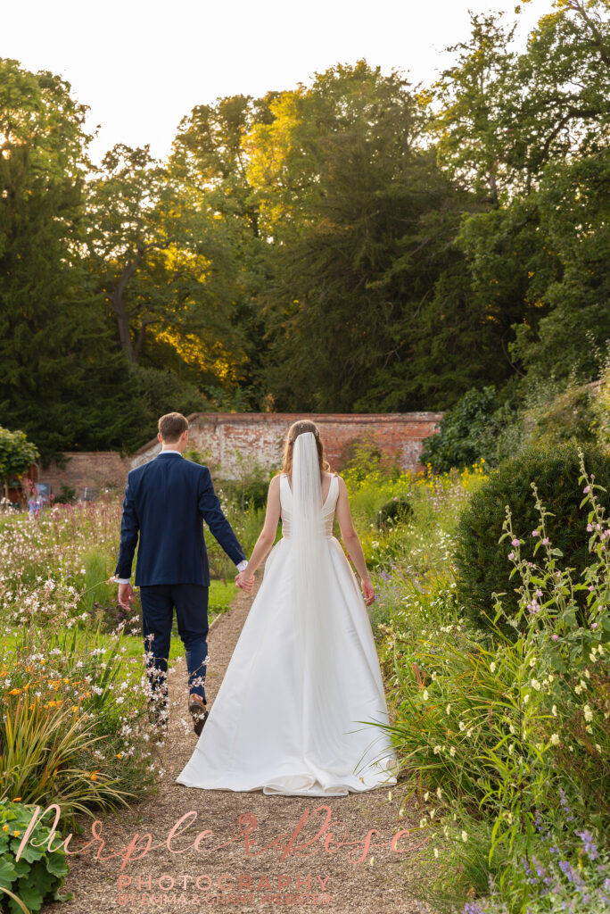 Photo of bride and groom walking away from the camera hand in hand on their wedding day in Milton Keynes