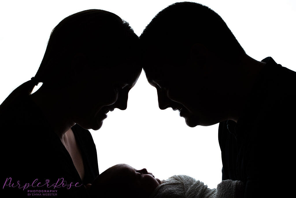 Silhouette of parents holding baby
