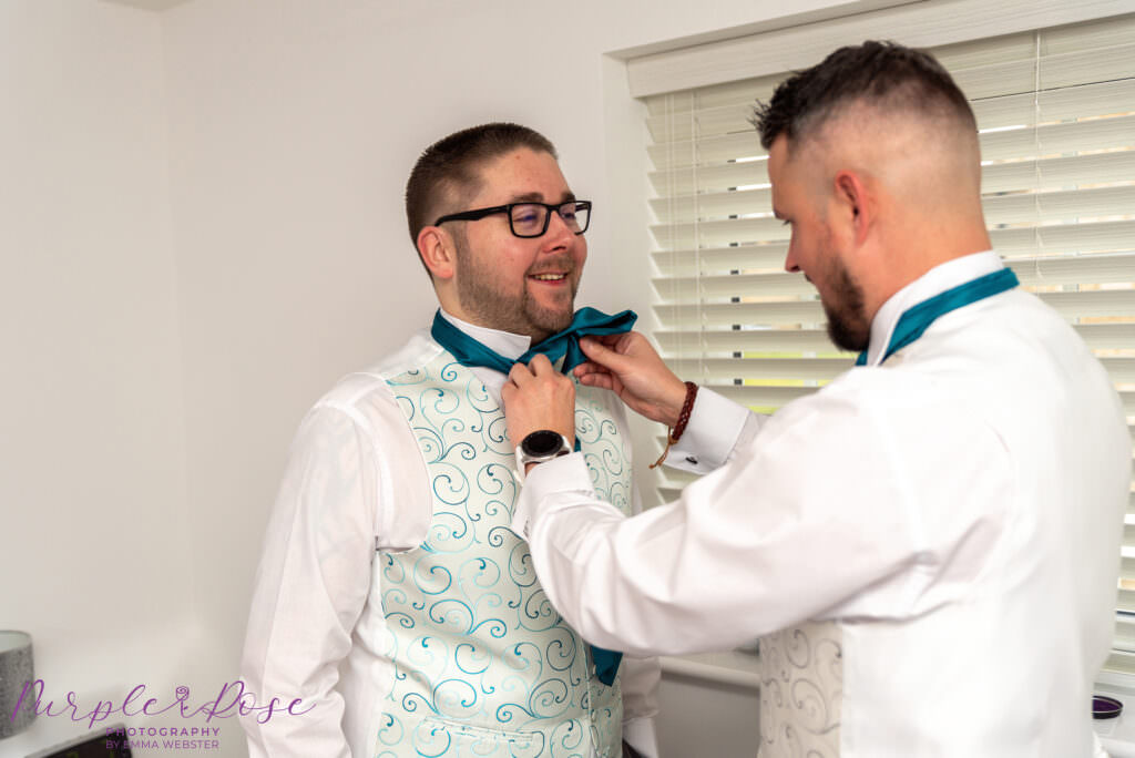 Best man adjusting grooms cravat