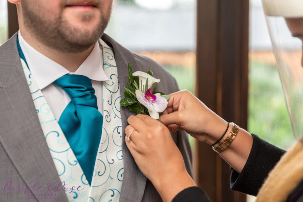 Groom having his buttonhole secured to his suit