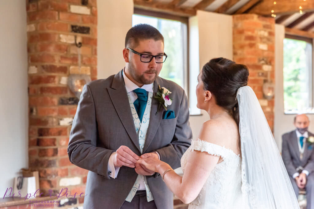 Groom placing ring on brides finger