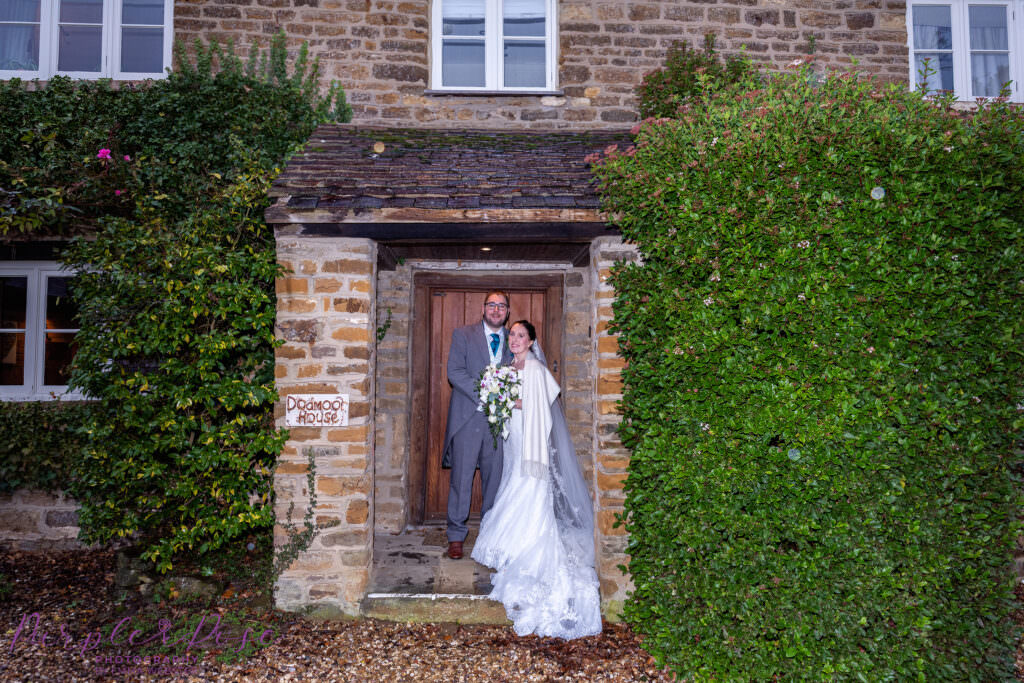 Bride and groom sheltering in a cottage door