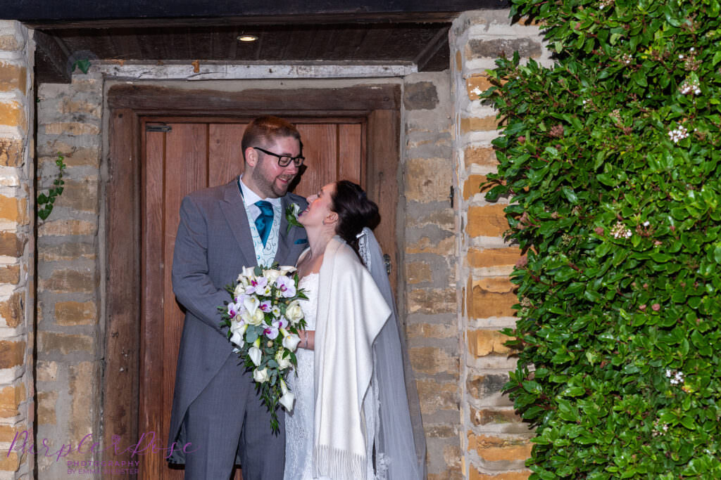 Bride and groom sheltering under the rain