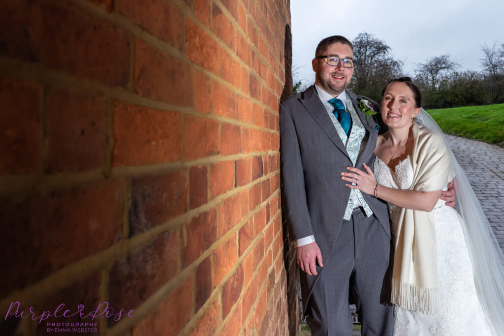 Bride and groom leaning on a wall