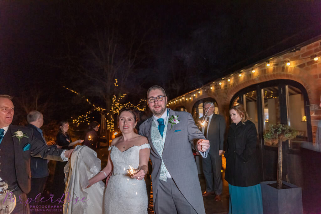 Bride, groom and guests playing with sparklers