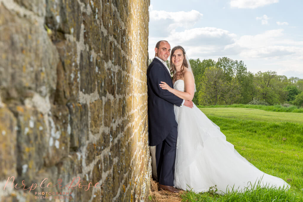 Bride and groom leaning on a brick wall