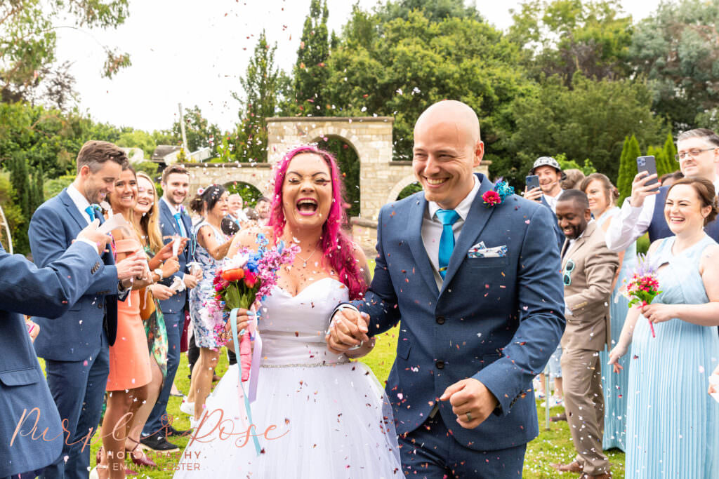 bride and groom having confetti thrown over them