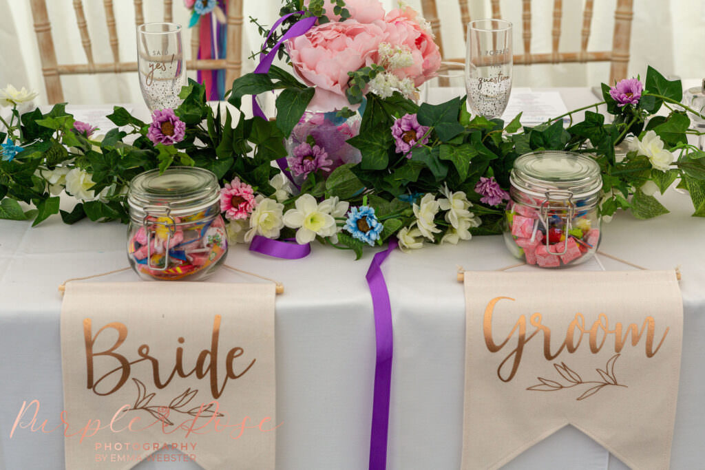 Head table with flowers and bride and groom sign