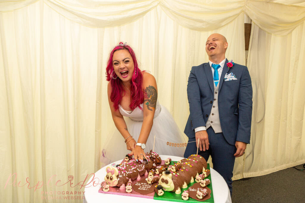 Bride and groom with their caterpillar wedding cake