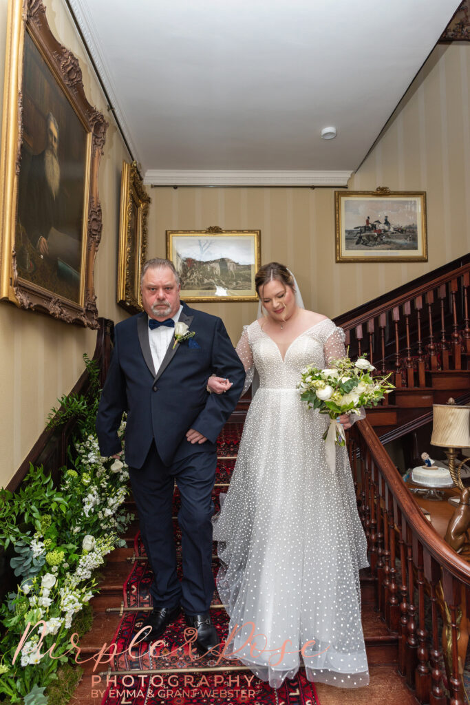 Photo of bride and father of the bride walking down a staircase on the way to the wedding ceremony in Milton Keynes