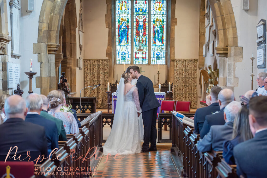 Photo of bride and grooms first kiss during their wedding ceremony in Milton Keynes