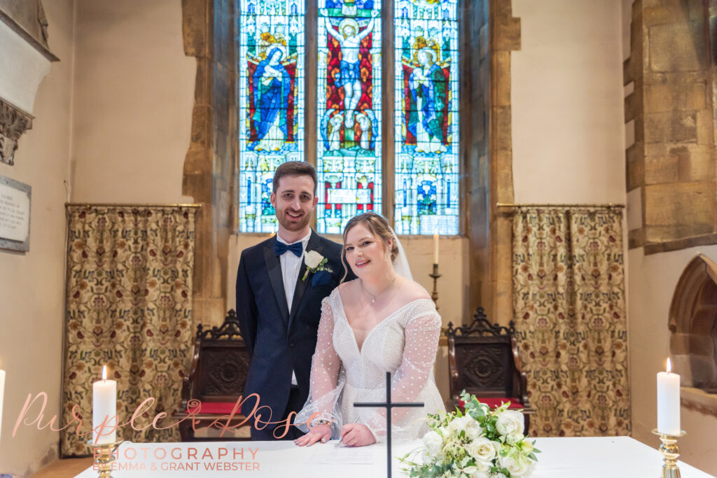 Photo of a bride and groom signing the registra on their wedding day in Milton Keynes
