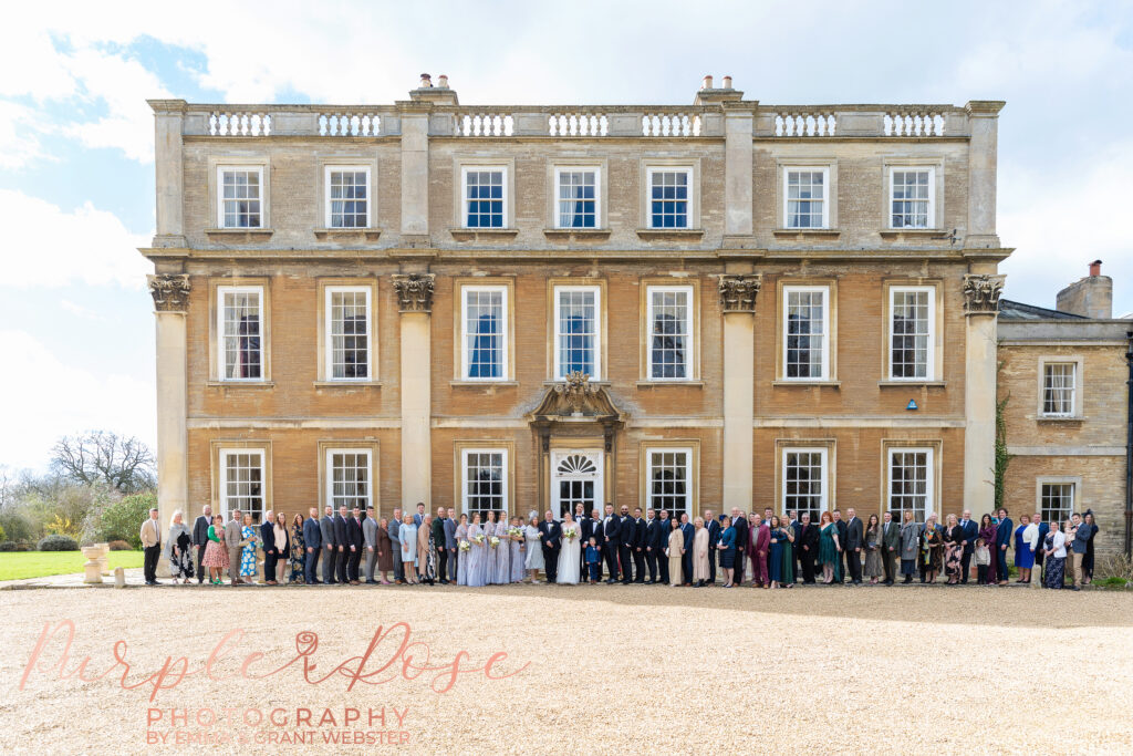 Group photo of all the guests at a wedding outside the venue in Milton Keynes