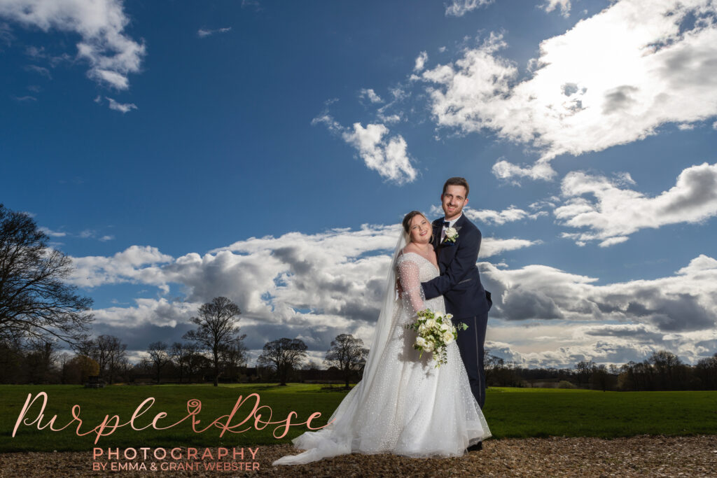 Photo of a bride and groom in front of stunning cloud filled sky on their wedding day in Milton Keynes