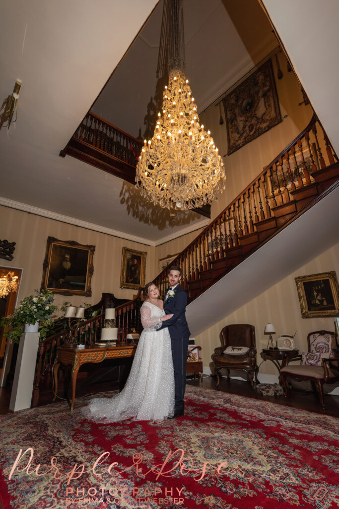 Photo of bride and groom under a chandalier on their wedding day in Milton Keynes