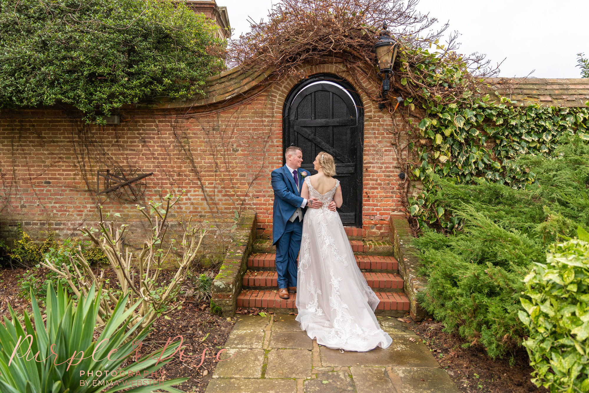 Bride and groom by garden gate