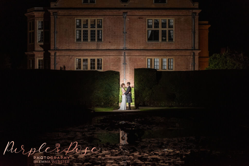 Night time photo of bride and groom in front of their wedding venue