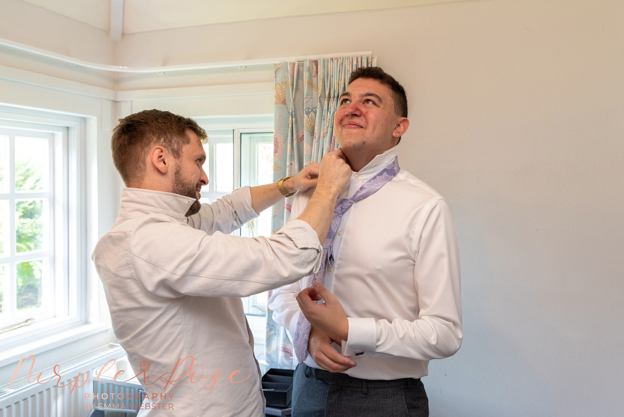 Grooms friend adjusting his tie 