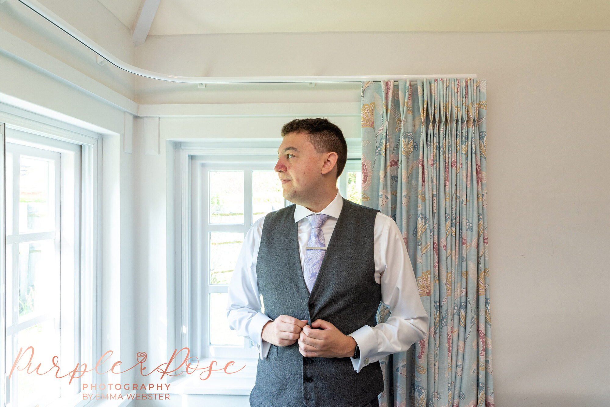 Groom buttoning up his waist coat