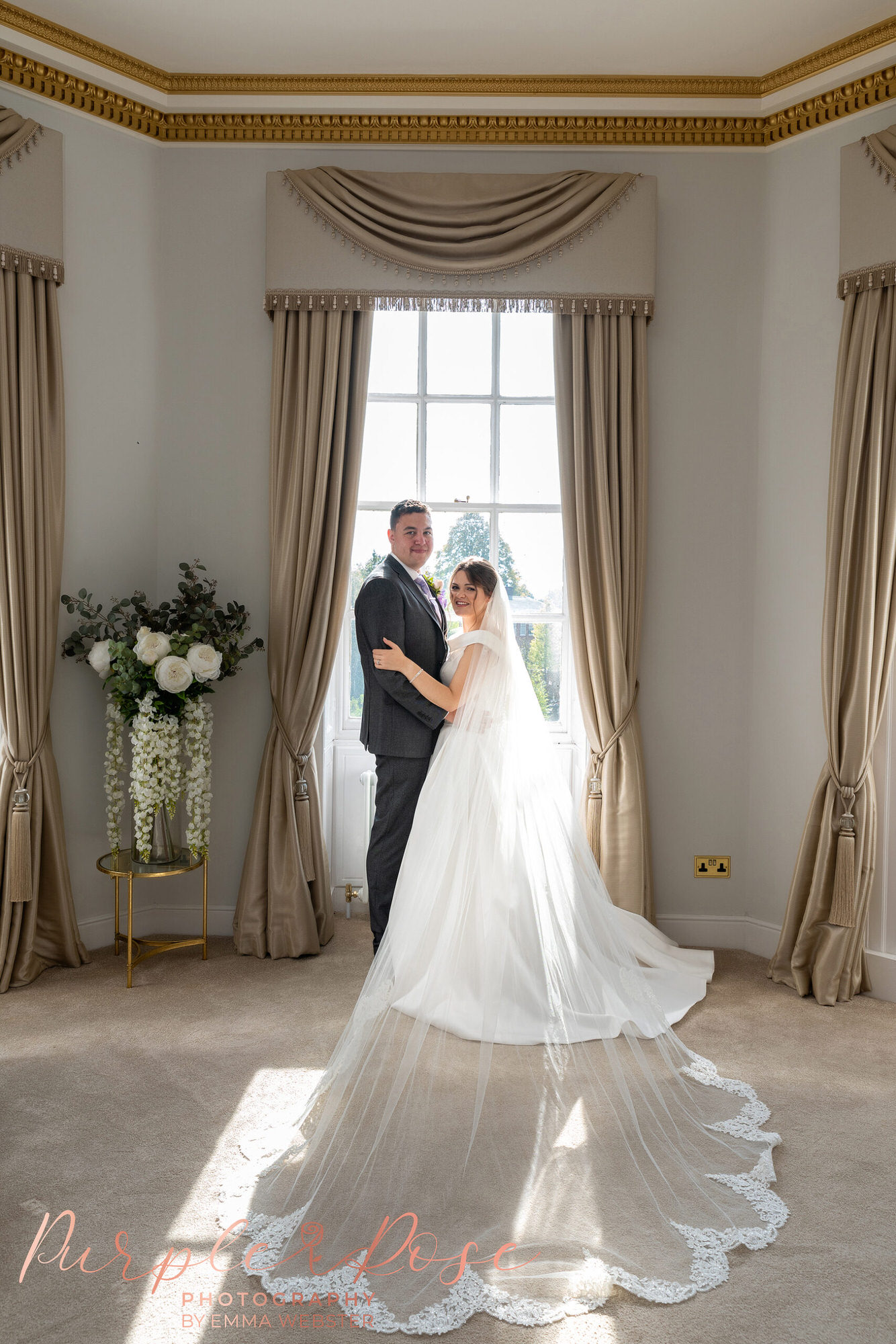 Bride and groom stood in front of a window