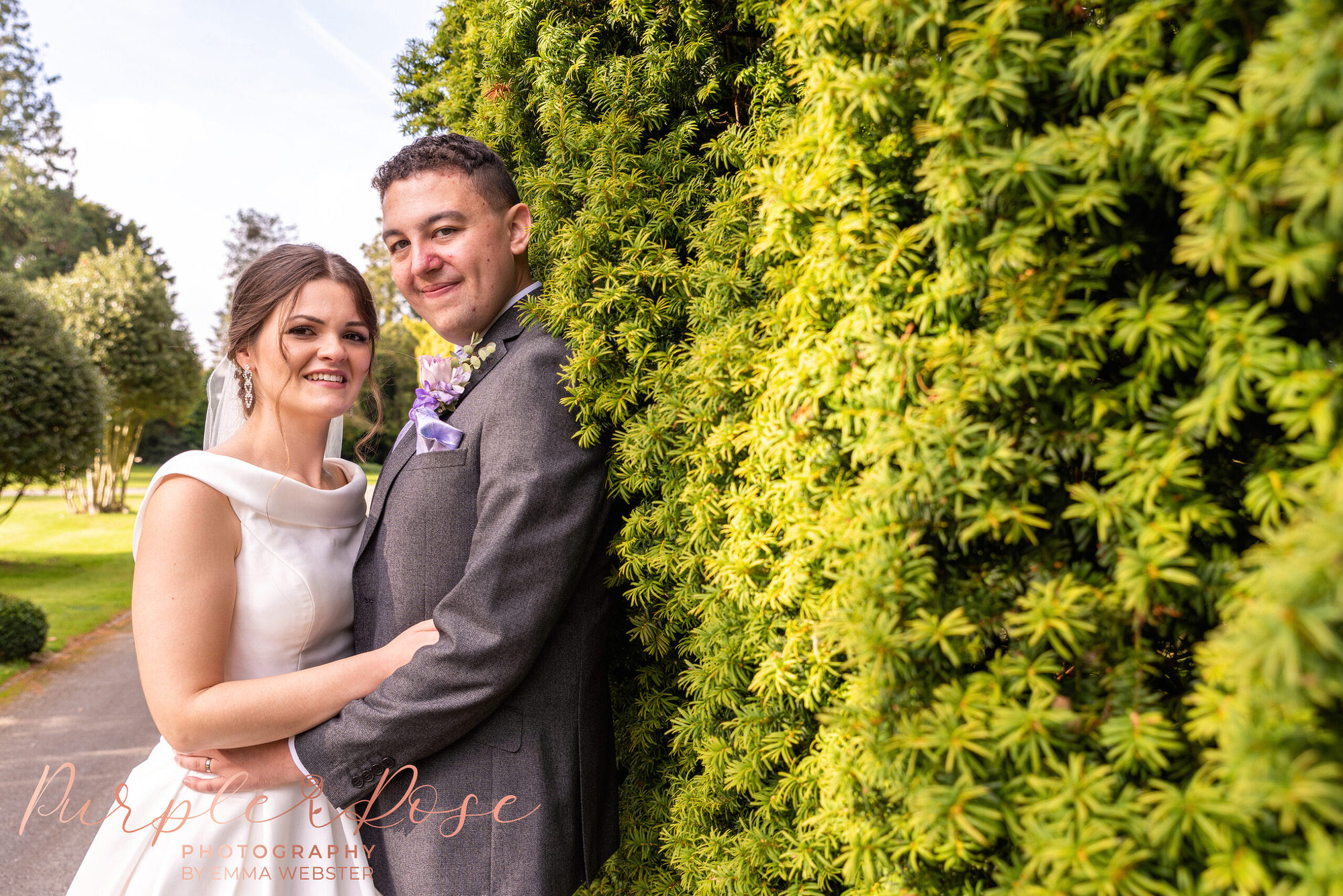 Bride and groom on a hedge lined path