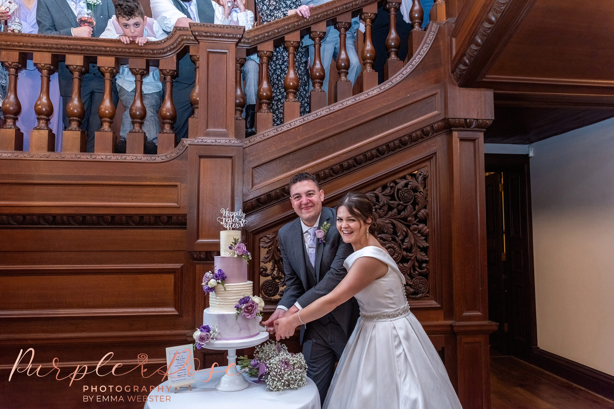 Bride and groom cutting their wedding cake by staircase