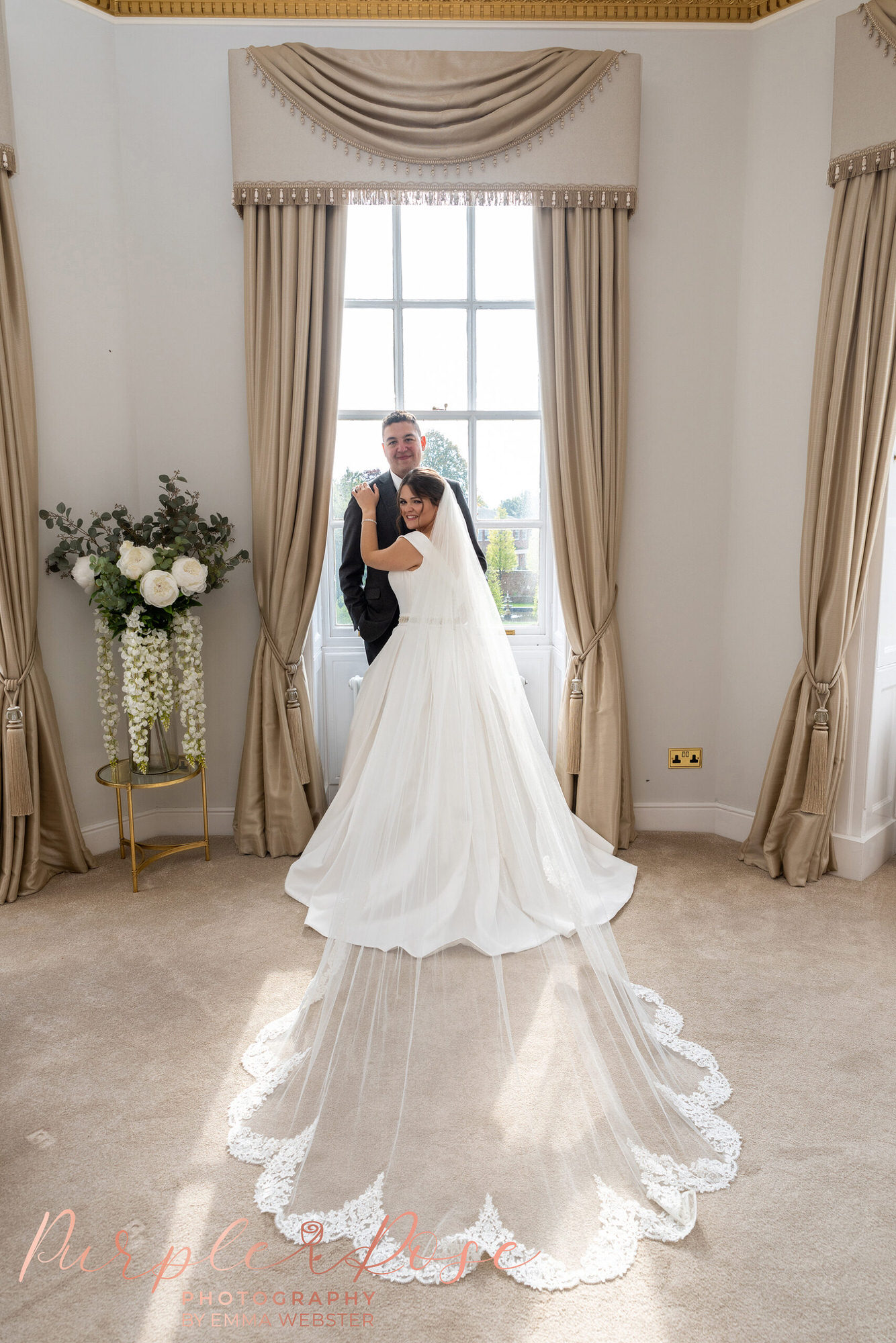 Bride and groom in front of a window