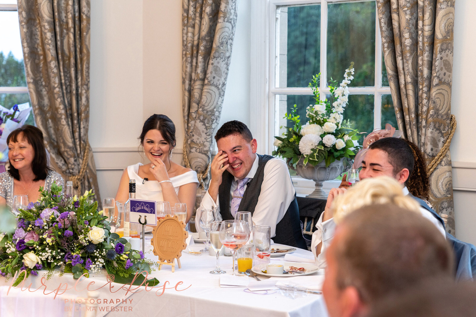 Bride and groom laughing during wedding speeches