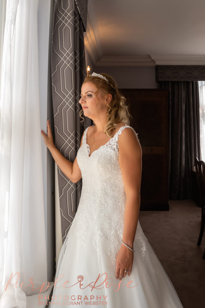 Bride looking out a wondow on her wedding day