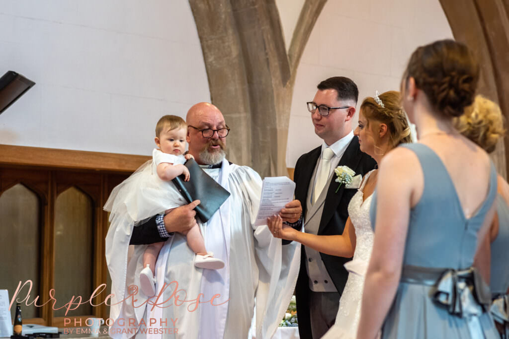 Priest holding child during wedding ceremony