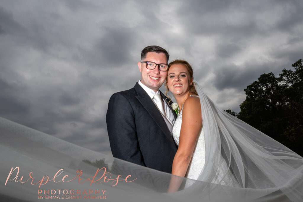 bride and groom smiling as her wedding veil swirls around them