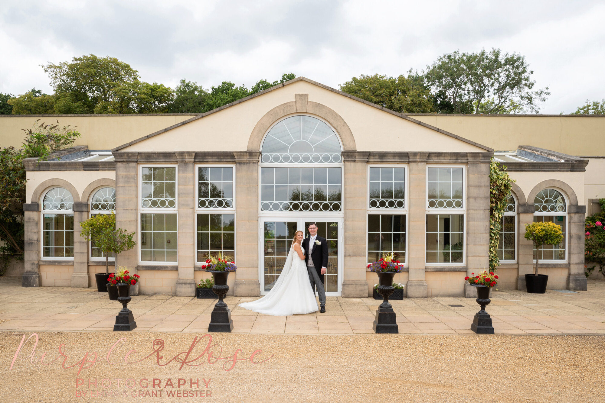 Bride and groom in front of an orangery during a photoshoot on their wedding day in Northampton