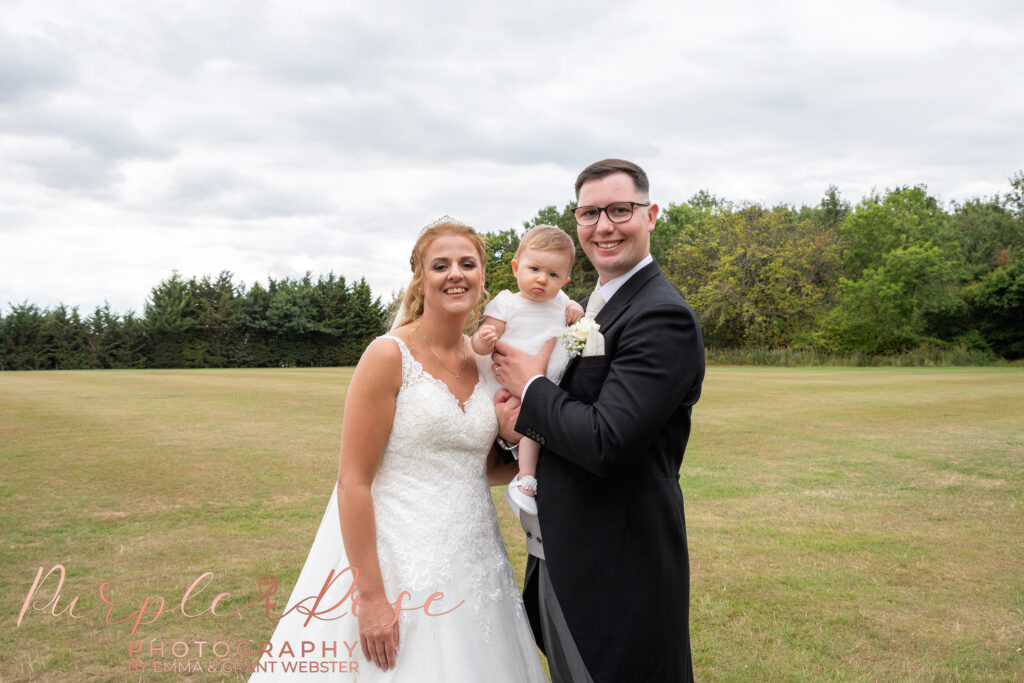 Bride and groom holding their daughter