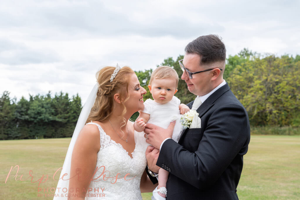 Bride and groom looking at their daughter