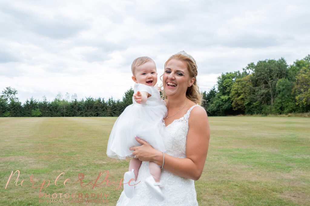 Bride laughing while holding her baby