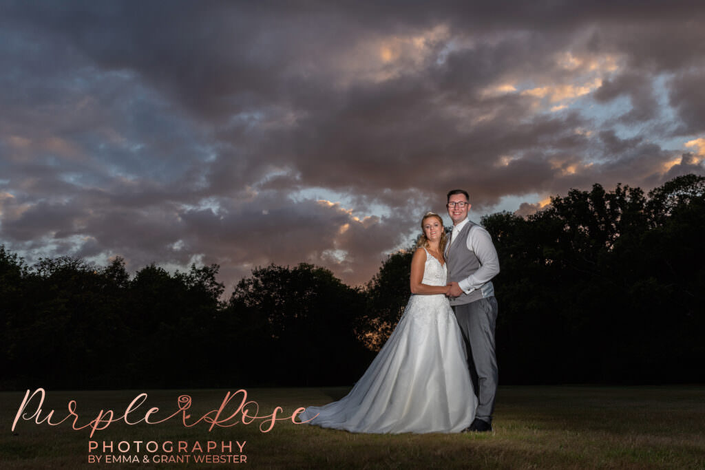 Bride and groom stood in front of a stormy sunset
