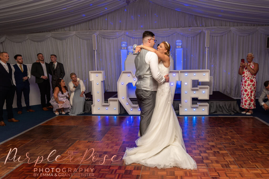 Bride and groom dancing in front of love letters