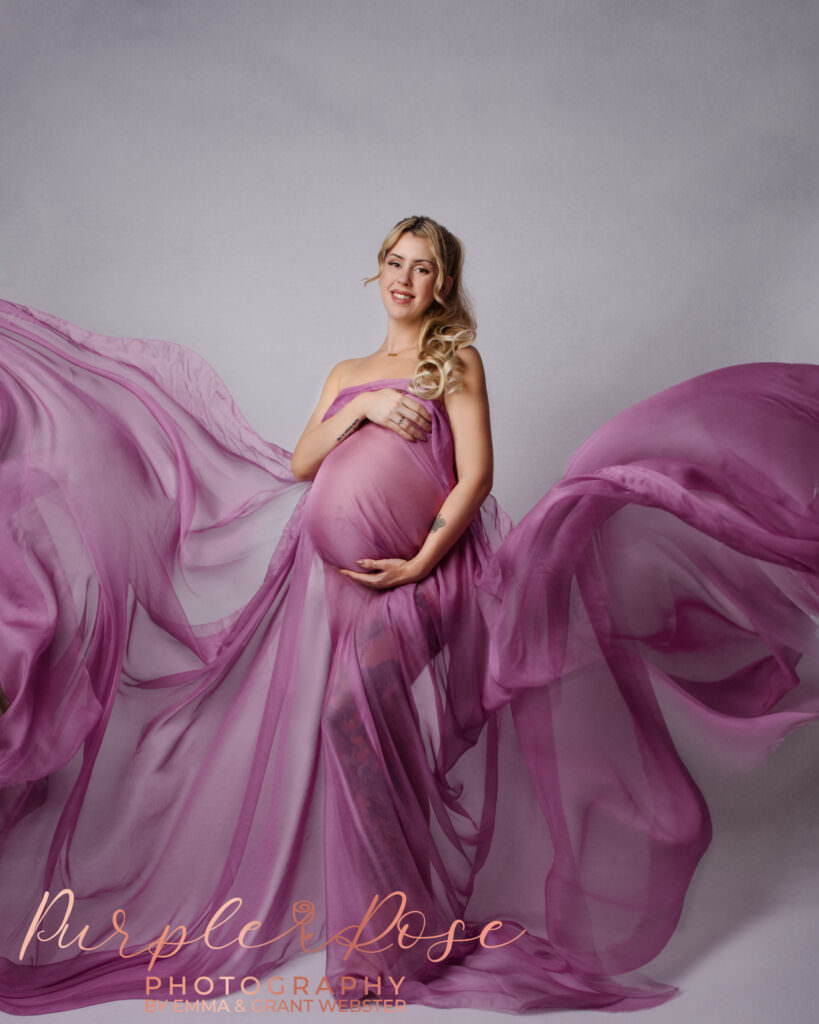 Mother with pink fanric swirling around her during her maternity photoshoot in Milton Keynes