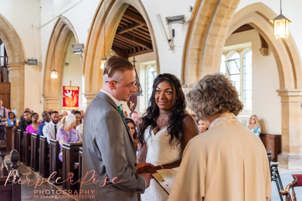 Photo of a bride and groom holding hands during their church wedding ceremony in Milton Keynes