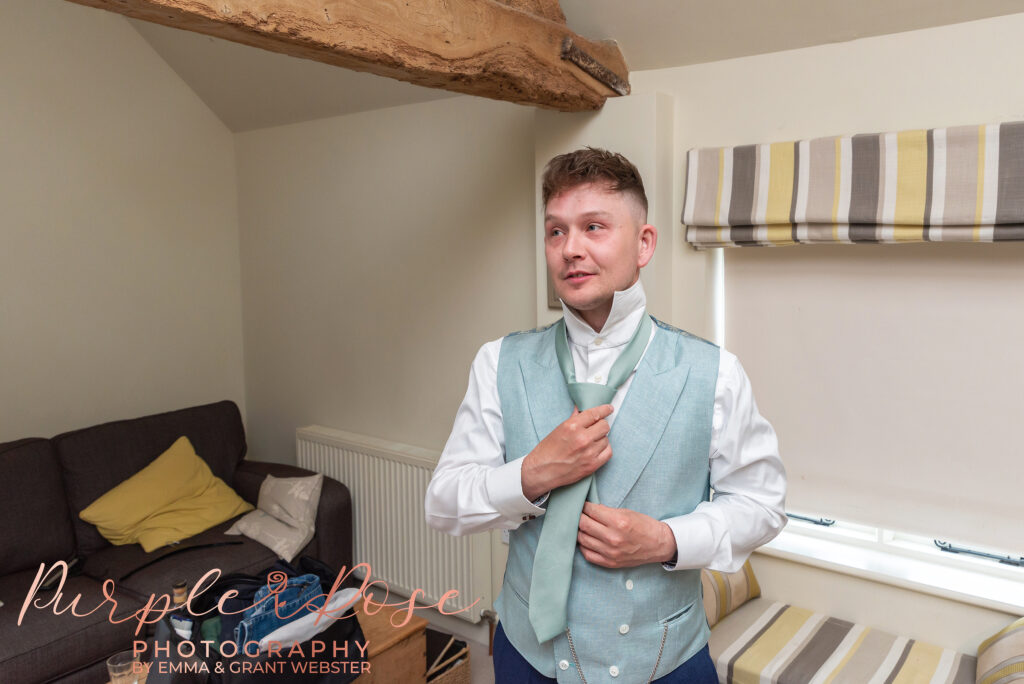 Photo of groom adjusting his tie on his wedding day in Northampton